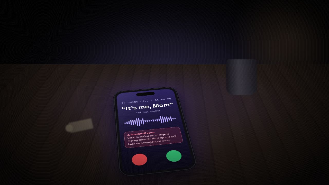 Illustration of a smartphone on a dark kitchen table at night showing an incoming call from an unknown number that says 'It's me, Mom', with a warning that the caller may be an AI voice asking for an urgent money transfer